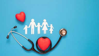 White paper dolls of a family on a blue background, with a stethoscope and read hearts.